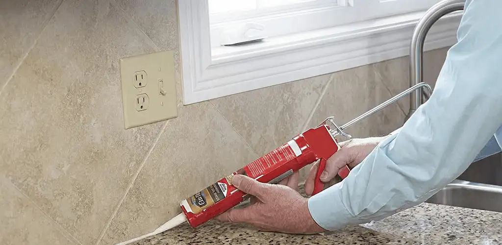 Handyman applying caulk along a kitchen backsplash and countertop seam in Fort Collins, CO