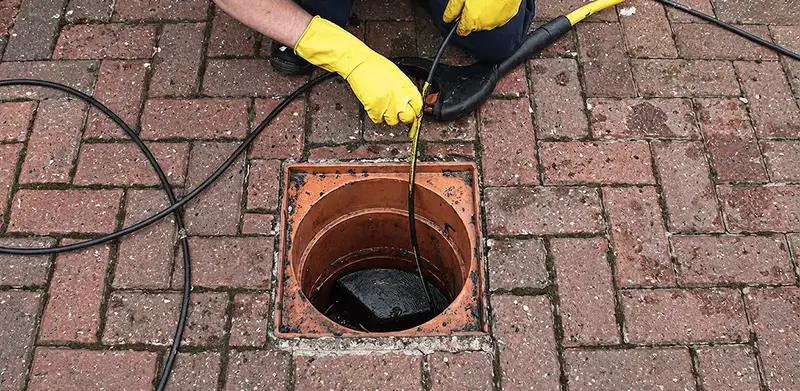 Drain cleaning technician using a drain snake to clear a clogged drain in Fort Collins, CO