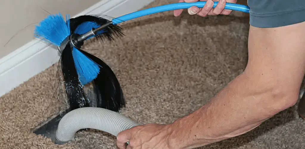 Dryer vent cleaning technician brushing lint from a vent line in Fort Collins, CO
