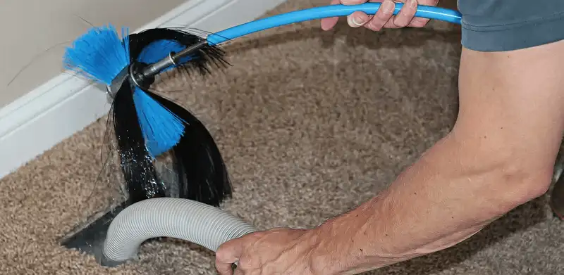 Dryer vent cleaning technician brushing lint from a vent line in Fort Collins, CO