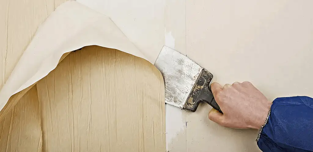 Handyman removing wallpaper with a scraper for wall preparation in Fort Collins, CO