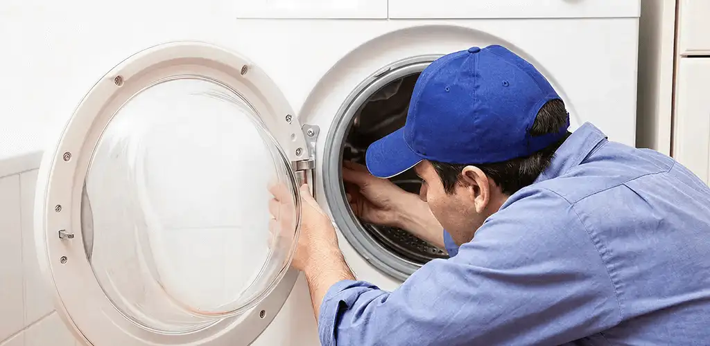 Washing machine repair handyman inspecting a front-load washer drum in Fort Collins, CO