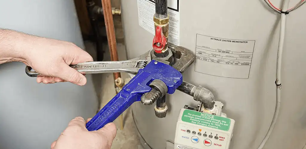 Water heater repair technician tightening the shutoff valve and supply line in Fort Collins, CO